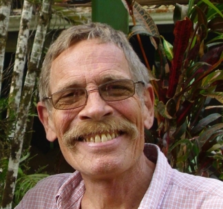 Steve Prchal, one of the founders of IECC. An older white man with a bushy ginger mustache. He is wearing square tinted glasses and smiling.