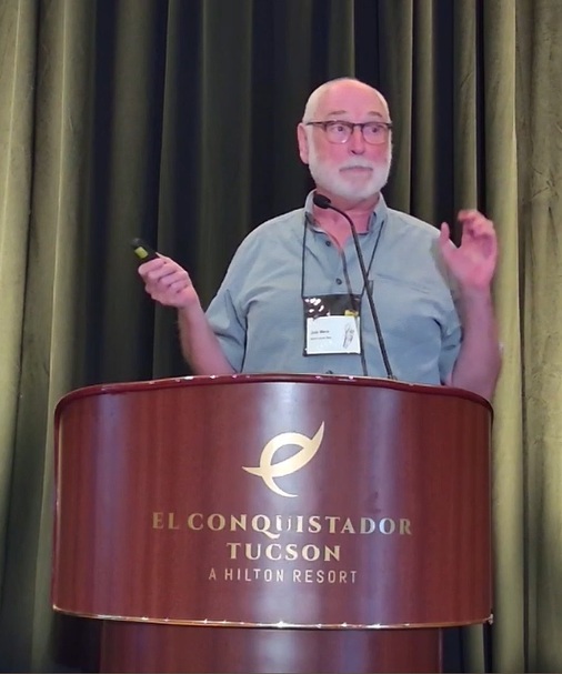 A man presenting a paper talk behind a podium at the IECC conference